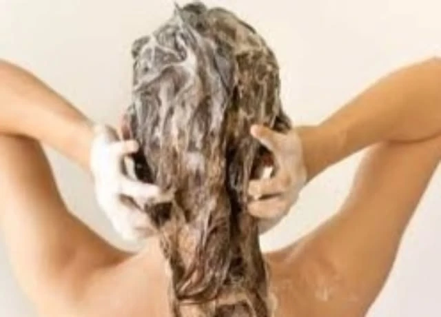 Hands working product through wet hair at the basin