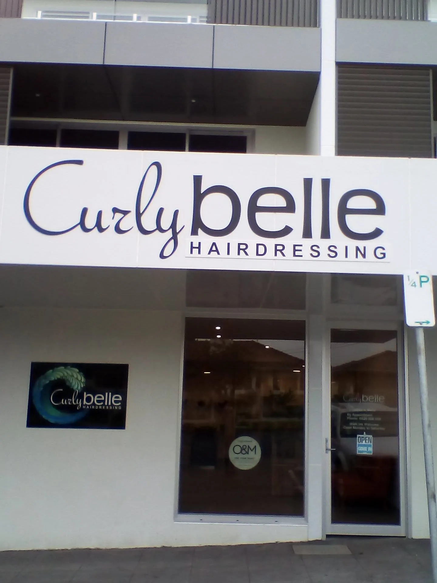 Curly Belle Hairdressing shopfront on Cavanagh St by day — signage, glass frontage, wave decal