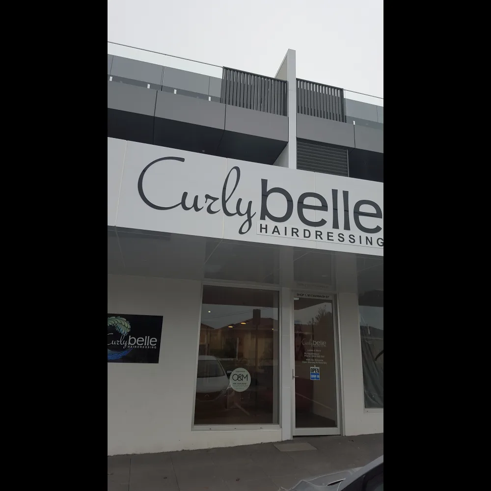 The Curly Belle shopfront at dusk with full signage and window decals